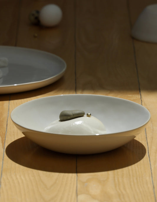 Fable pearl white stoneware pasta bowl and plate styled on a warm wood table in sunlight
