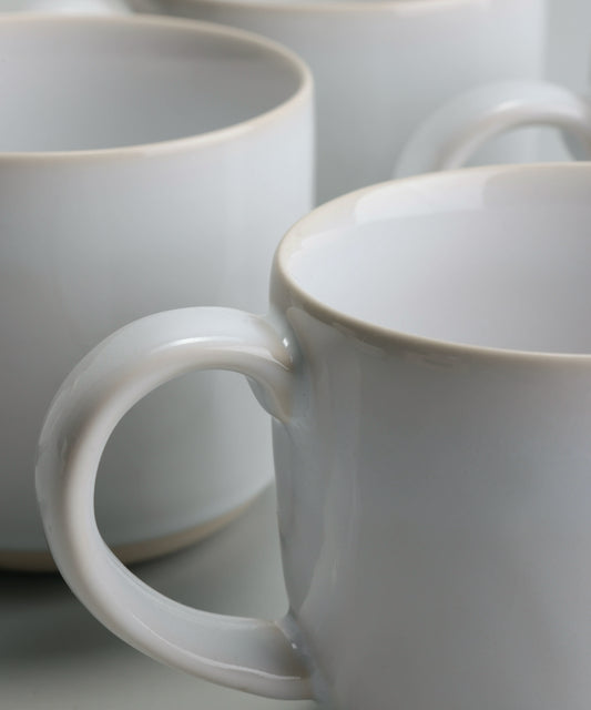 Close-up of Fable Pearl White ceramic mugs grouped on a pale grey surface