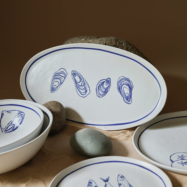 Set of ceramic plates with blue shell designs on a wooden surface