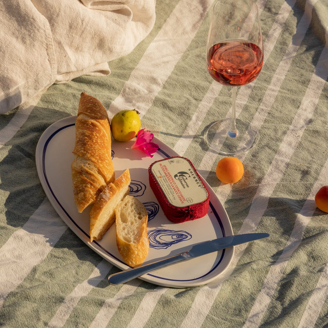 Heart-shaped plate with bread, butter, and a glass of pink wine on a checkered tablecloth.