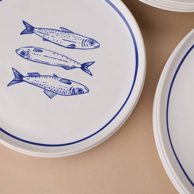 White plates with blue fish illustrations on a beige surface